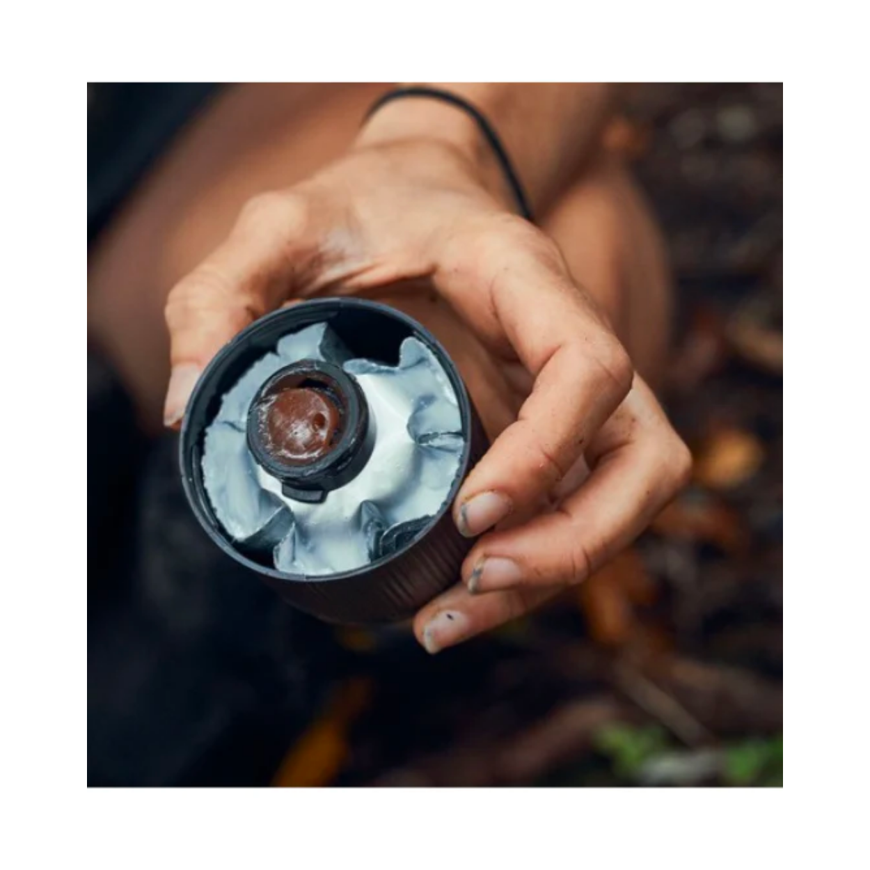 A persons hand holding the Goodnature chocolate automatic pump paste.